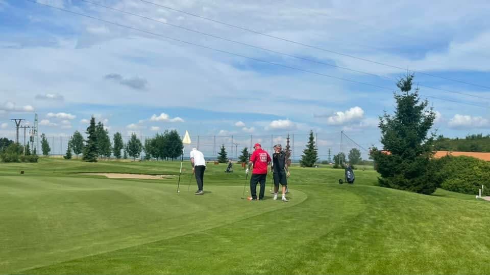 Účastníci golfového turnaje na greenu